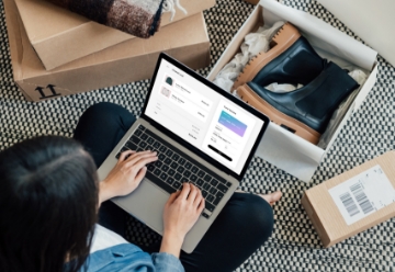 Woman sitting cross-legged with her laptop surrounded by online shopping packages