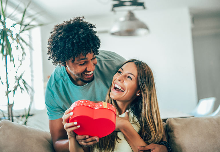 A couple giving/receiving a Valentine's day present in a red heart-shaped box