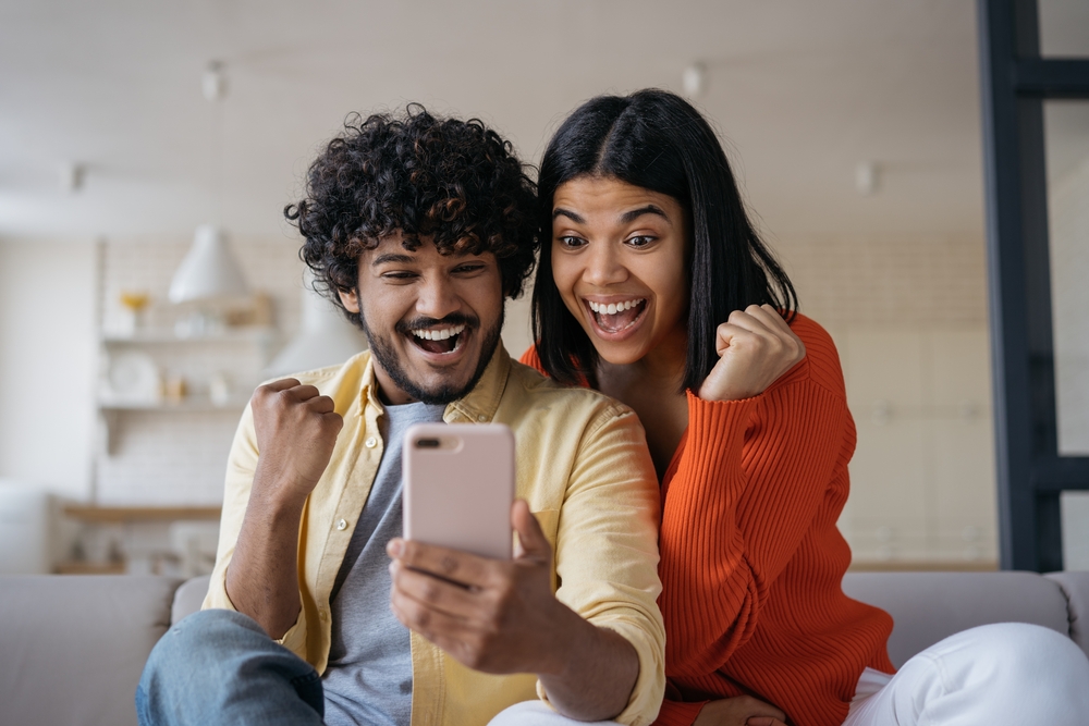 Couple looking at a phone with big smiles on their faces