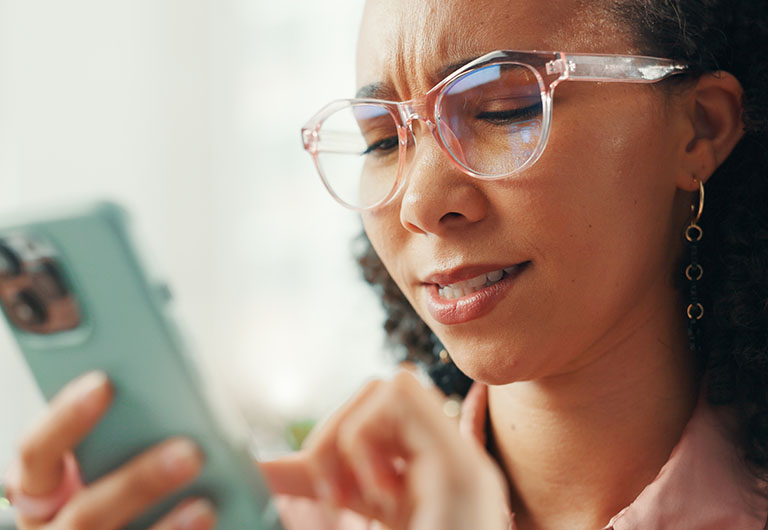 Woman swiping on phone with a skeptical expression