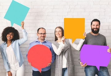 Group of happy diverse people holding colourful speech bubbles and smiling at camera