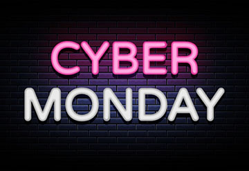 "CYBER MONDAY" written in neon pink and white lights against a black brick wall background