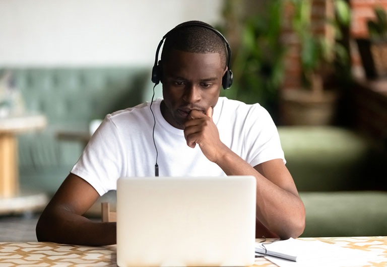 Young man working on his laptop with headphones in a home setting