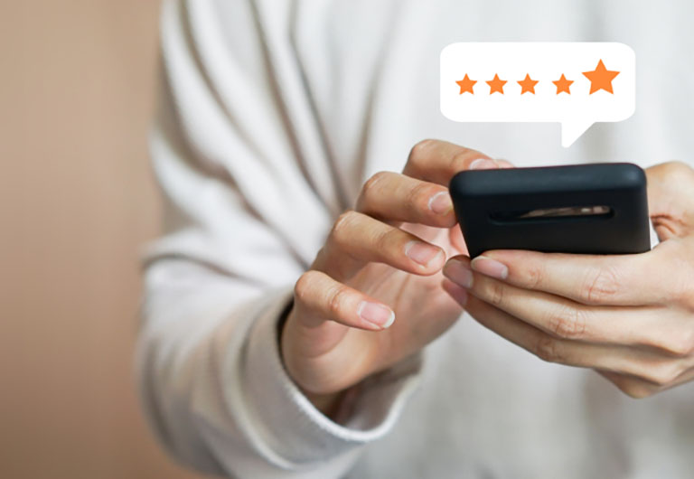 Man holding smartphone with a speech bubble above it containing 5 stars last of which is larger than the rest