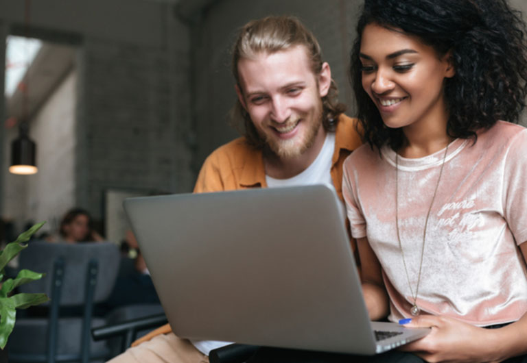 Man and woman looking at a laptop smiling