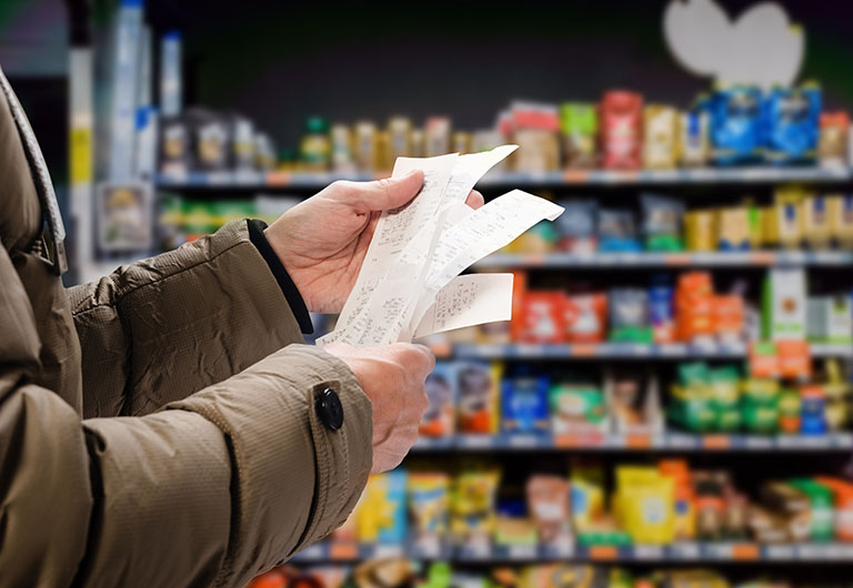 Man viewing receipts in supermarket and tracking prices