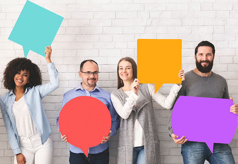 Group of happy diverse people holding colourful speech bubbles and smiling at camera