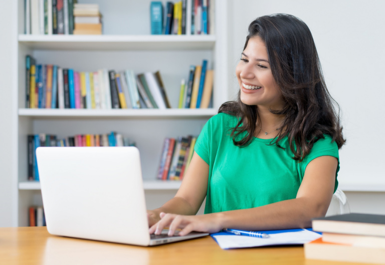 mujer latina sonrie mientras mira su laptop