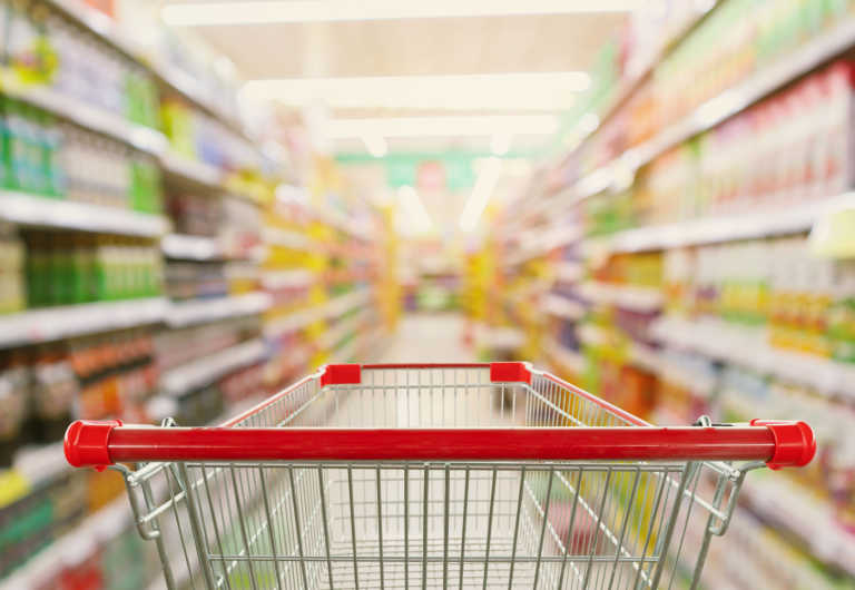 supermarket aisle interior blur background with empty red shopping cart