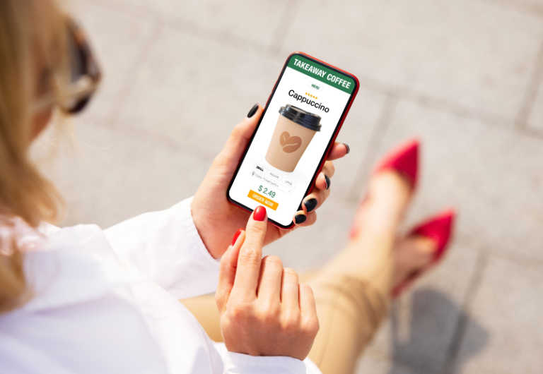 Woman ordering coffee online for takeaway on mobile phone