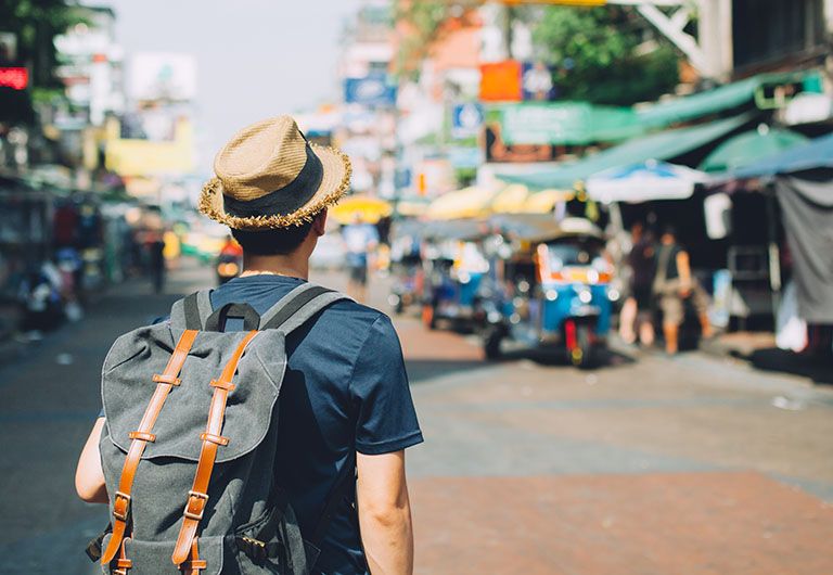 traveller with a backpack and a hat walking on an urban street