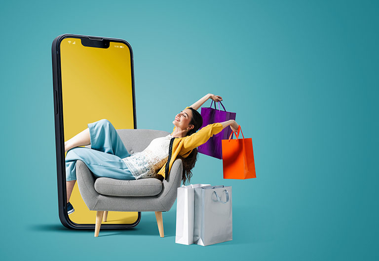 Abstract setting with woman reclining on an armchair holding shopping bags with her legs disappearing into a giant mobile phone