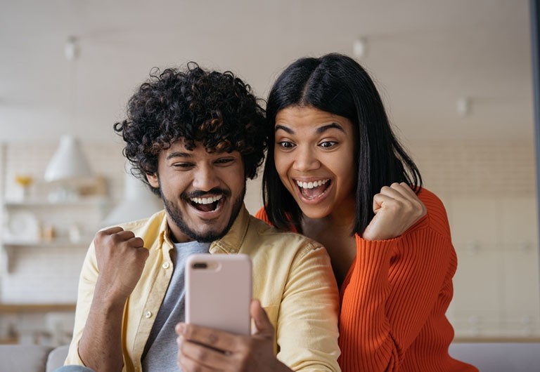 Couple looking at a phone with big smiles on their faces